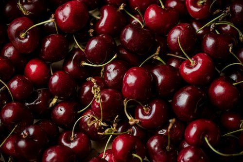 Dark+Cherries+Fresh Fresh arugula leaves on a wooden cutting board with a knife in the background, ideal for healthy cooking and salad preparation.